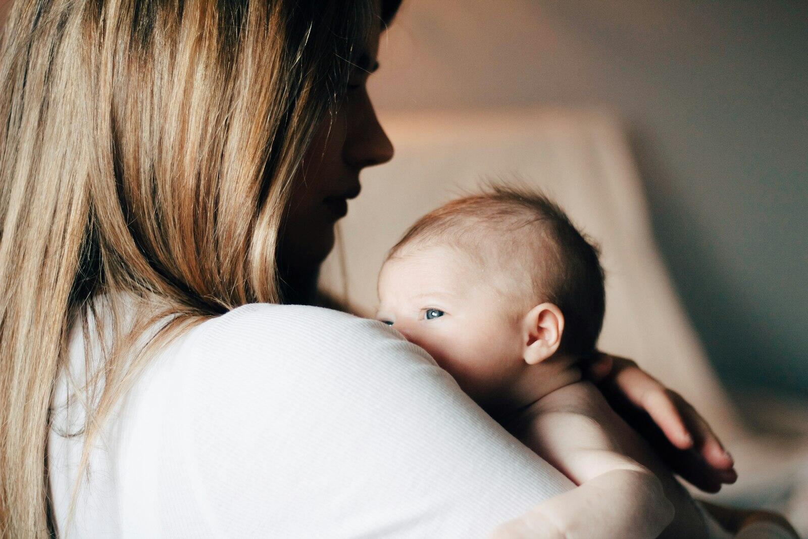 Mutter hält ihr Baby ruhig an der Schulter